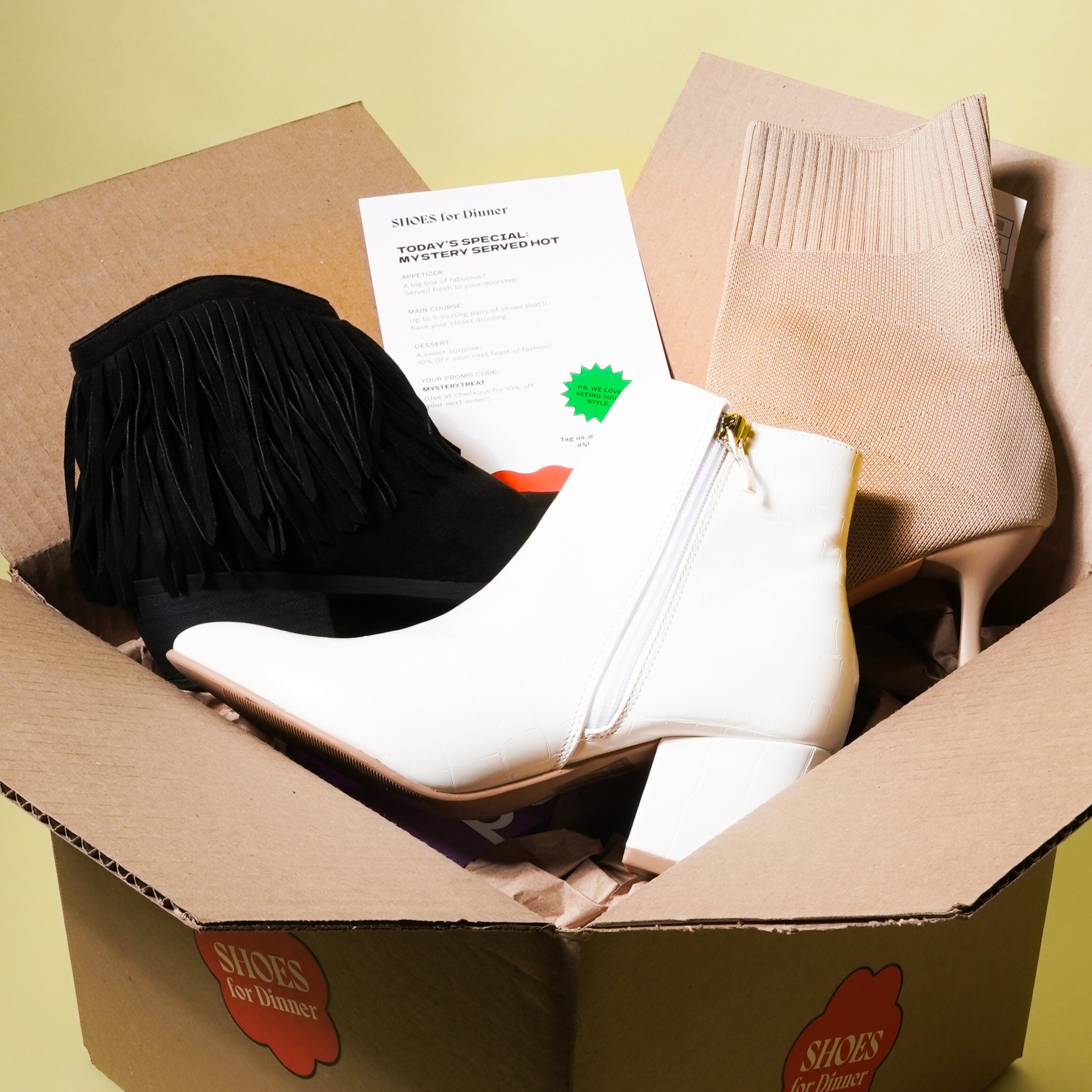 Three pairs of ankle boots in a box on a yellow background