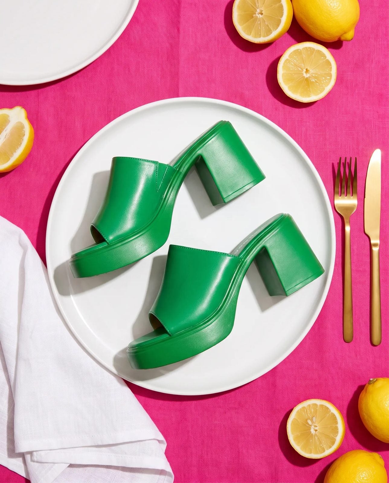 Nasty – Green platform mules served on a white dinner plate on a hot pink tablecloth, top view